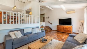A spacious living room with a grey sofa, a wooden coffee table, and a TV on a wooden cabinet.