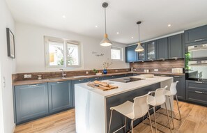 A modern kitchen with a central island, bar stools, and built-in appliances. - Maison Marguerite - Five Bedroom Villa, Sleeps 10 (Limoux)