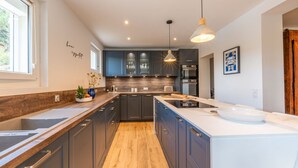 A modern kitchen with dark cabinets, a wooden countertop, and a large island.