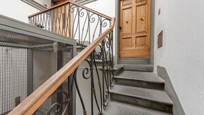 A staircase with a wooden handrail and metal balusters, leading to a wooden door with a metal handle.