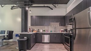 Una cocina moderna con armarios oscuros, electrodomésticos de acero inoxidable y lavavajillas.