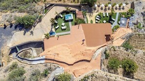 Vista aérea de un resort con piscina, tumbonas y un jardín paisajístico.
