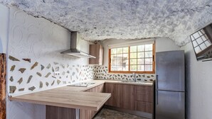 A kitchen with a stone backsplash, wooden cabinets, a stainless steel refrigerator, and a window with a view.