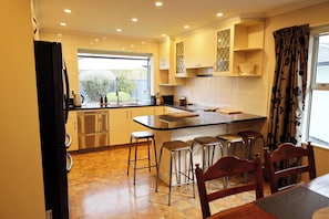 A modern kitchen with a central island, bar stools, stainless steel appliances, and a window with a view.