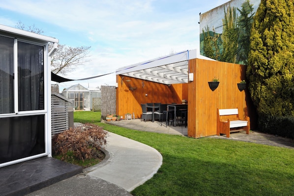 A modern building with a covered patio, outdoor seating, and a mural.