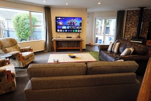A living room with a TV, sofa, and armchairs.