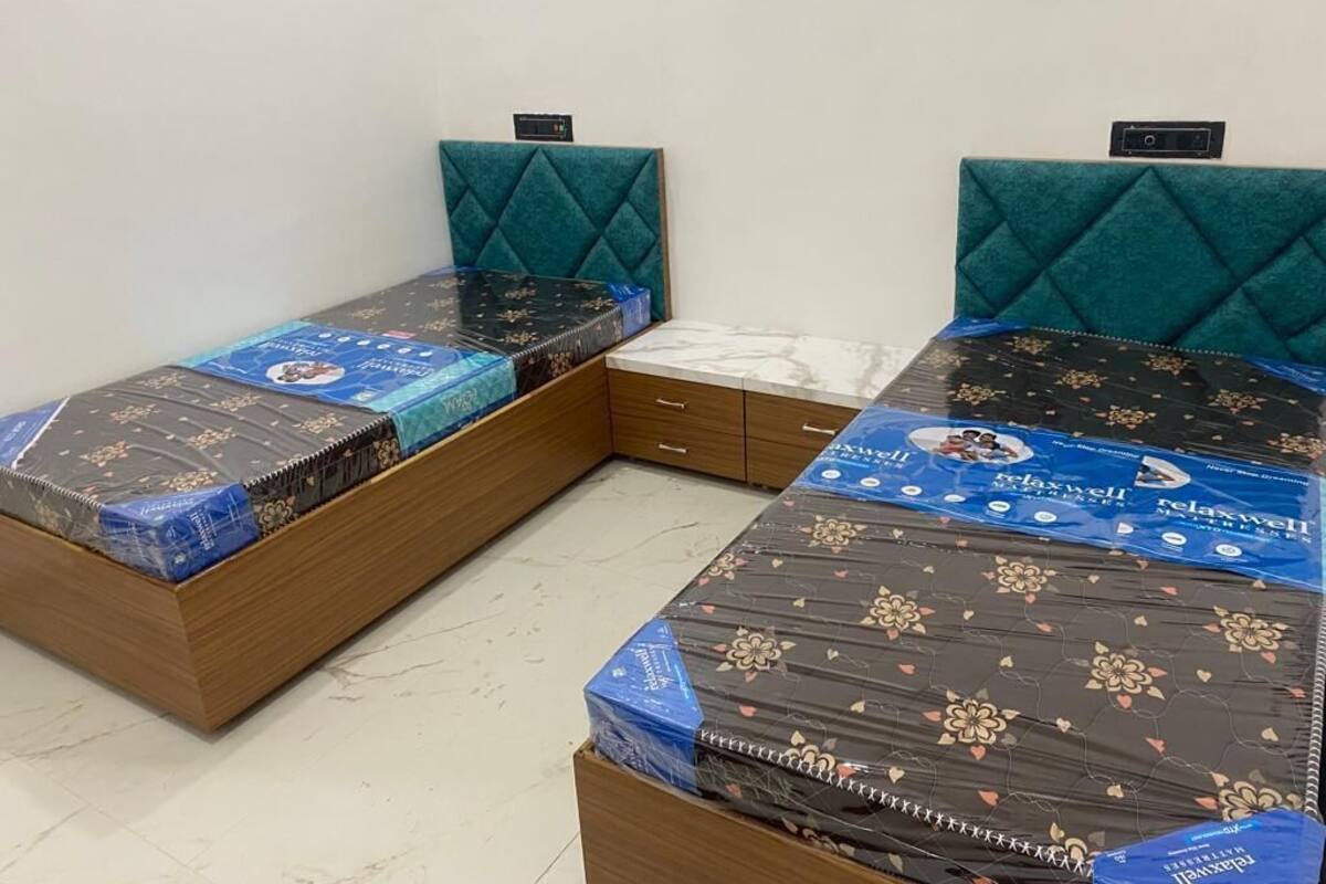 Two single beds with headboards, a small drawer unit, and a tiled floor.