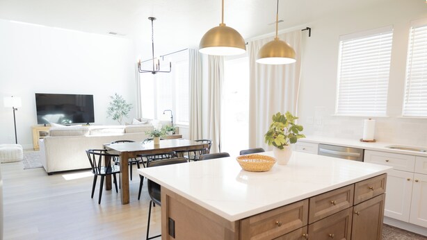 Une cuisine moderne dotée d’un grand îlot central, de meubles en bois et de luminaires suspendus.