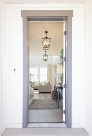A doorway leading to a living room with a sofa, a rug, and a hanging light fixture. - National Park Launching Pad  - 3 beds 2.5 baths - Tesla Charger (Cedar City)