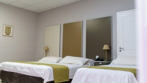 Quarto de hotel com duas camas, um espelho grande e uma mesa de cabeceira com abajur.