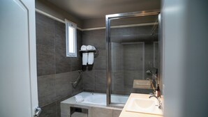 Uma casa de banho moderna com cabine de duche em vidro, banheira e lavatório.