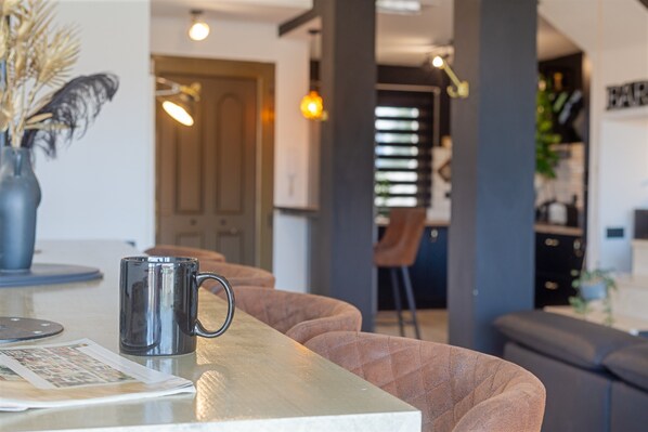 Eine moderne Küche mit Essbereich, einem Couchtisch mit Tasse und einer Bar im Hintergrund.