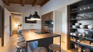 Een moderne keuken met een centraal eiland, barstoelen en een ingebouwde wijnrek.