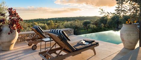 A sunlit outdoor area with a pool, lounge chairs, and large planters.