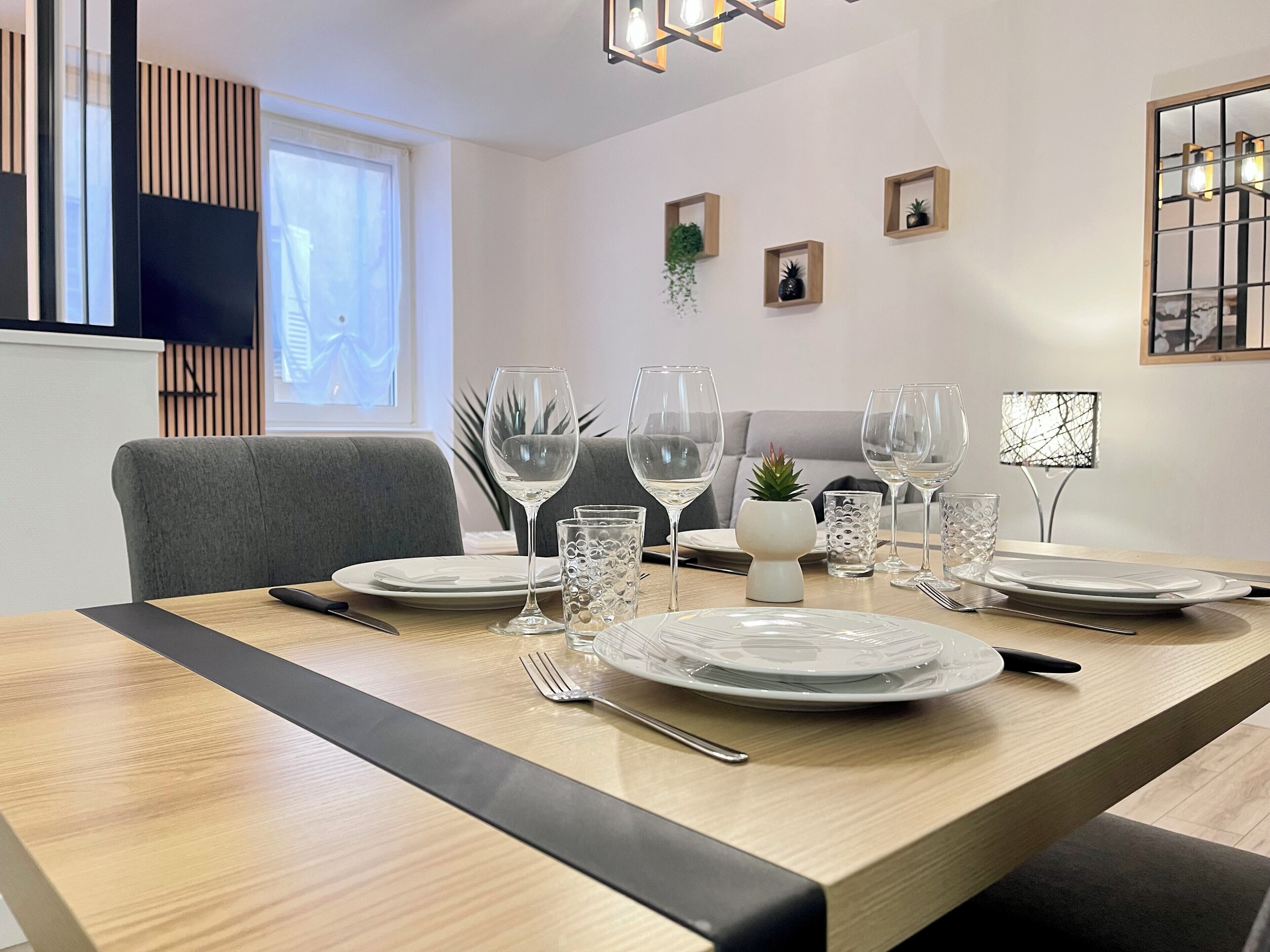 A dining area with a wooden table set for four, including plates, glasses, and cutlery.