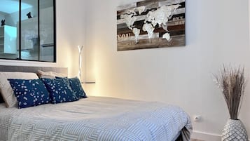 Un dormitorio con una cama, un cuadro de un mapa del mundo, una lámpara de pie alta y un jarrón decorativo.