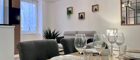 A dining area with a wooden table set for two, complete with plates, cutlery, and glasses.