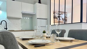 Un comedor moderno con una mesa de madera dispuesta para cuatro personas, platos blancos, vasos transparentes y cubiertos.