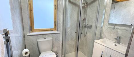 Ein modernes Badezimmer mit Duschkabine, Toilette, Waschbecken und Fenster.