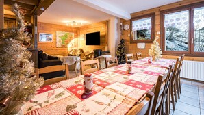 A cozy room with a wooden interior, a dining table with a quilt, a Christmas tree, and a fireplace.