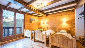 A wooden cabin bedroom with two beds, a balcony, and a wooden ceiling.