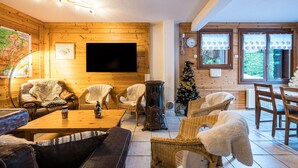 A cozy room with wooden walls, a flat-screen TV, wicker furniture, and a Christmas tree.