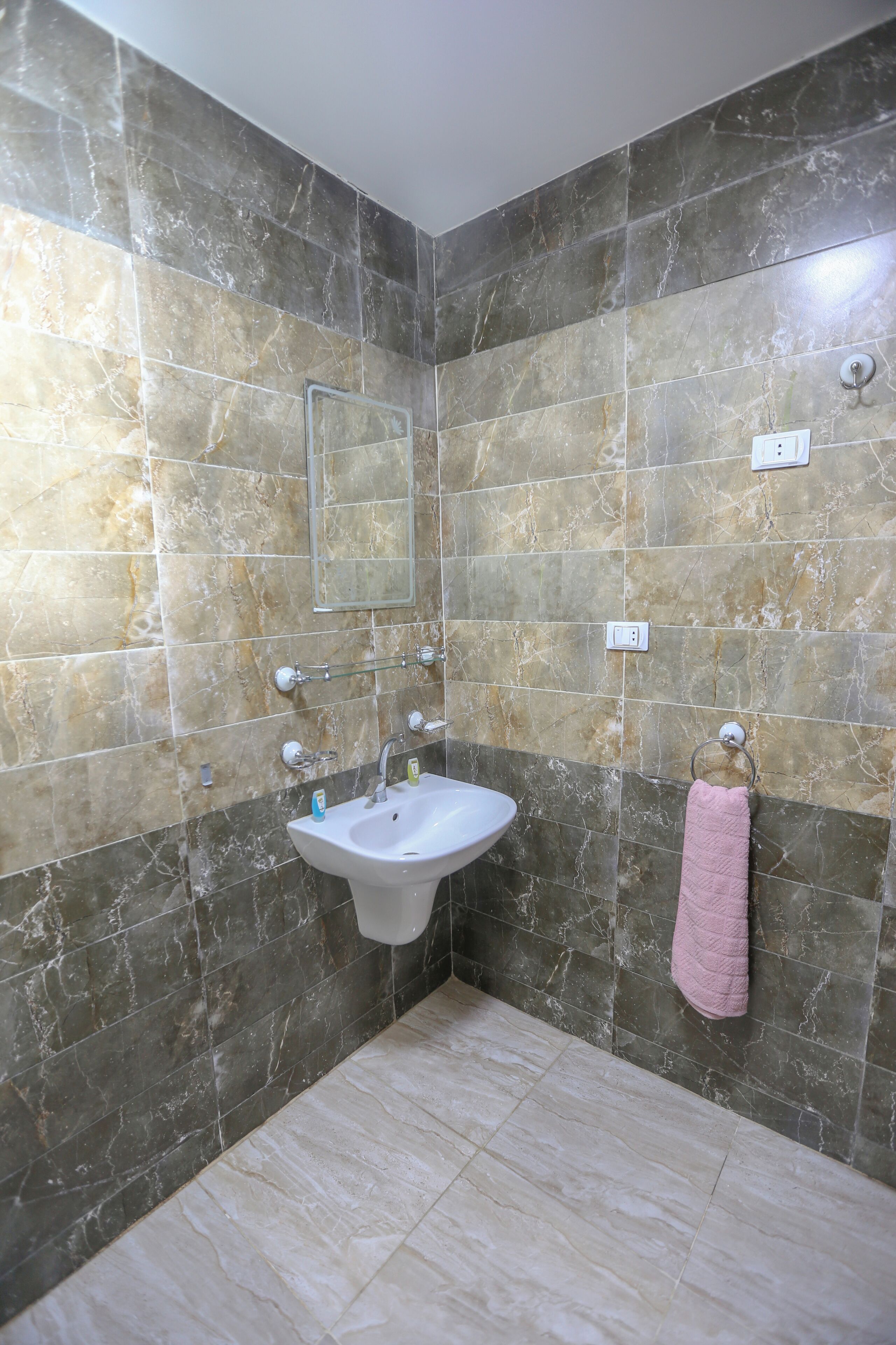 A bathroom with a marble wall, a sink, and a towel rack.