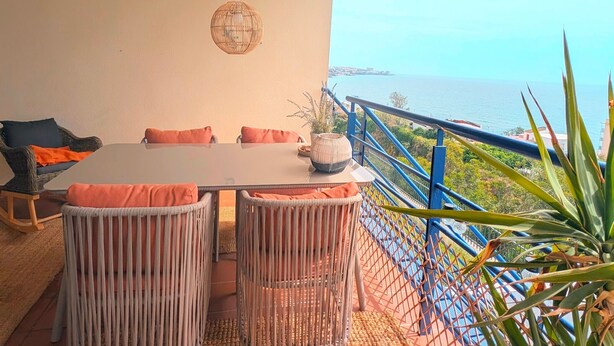 Un espace repas comprenant une table et des chaises, un luminaire suspendu et une vue sur la mer.