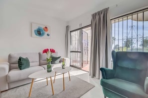 A modern living room with a sofa, a green armchair, a coffee table, and a painting on the wall.