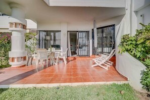 A covered patio with a dining table, chairs, and a lounge chair. - Apartment 'Calahonda Park' with Sea View, Wi-Fi and Air Conditioning (Calahonda)