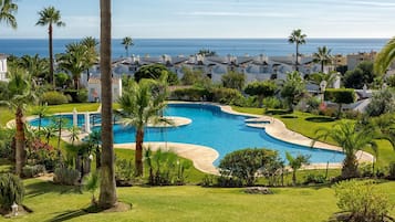 Ein Resort mit großem Pool, Palmen und Blick aufs Meer.