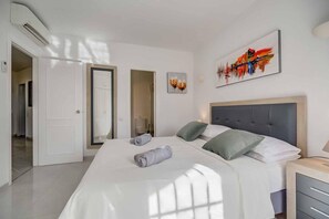 A modern bedroom with a large bed, a bedside table, a wall-mounted artwork, and a door leading to another room. - Apartment 'Calahonda Park' with Sea View, Wi-Fi and Air Conditioning (Calahonda)