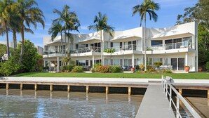 Un hotel de varios pisos con balcones, una zona de piscina y palmeras.
