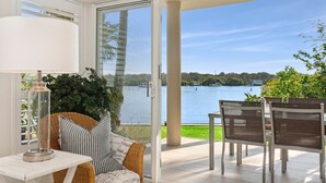 Un balcón con vistas a un lago, muebles de mimbre y una mesa con lámpara.