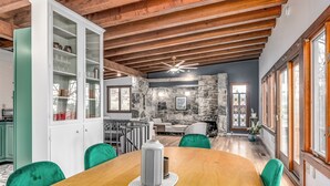 A dining area with a wooden table, green chairs, and a white cabinet with glass doors. - Stone Cabin on Valley View: Fire Pit + Hot Tub (Harpers Ferry)