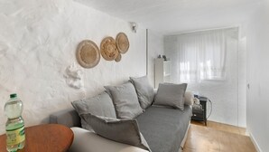 Ein Wohnzimmer mit einem grauen Sofa, einem Holztisch und einer Wasserflasche.