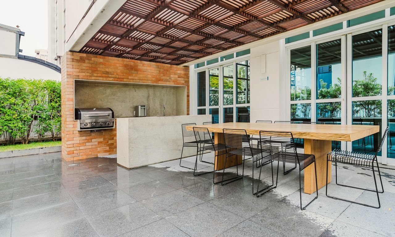 Un patio al aire libre con una parrilla, una mesa de madera grande y sillas.