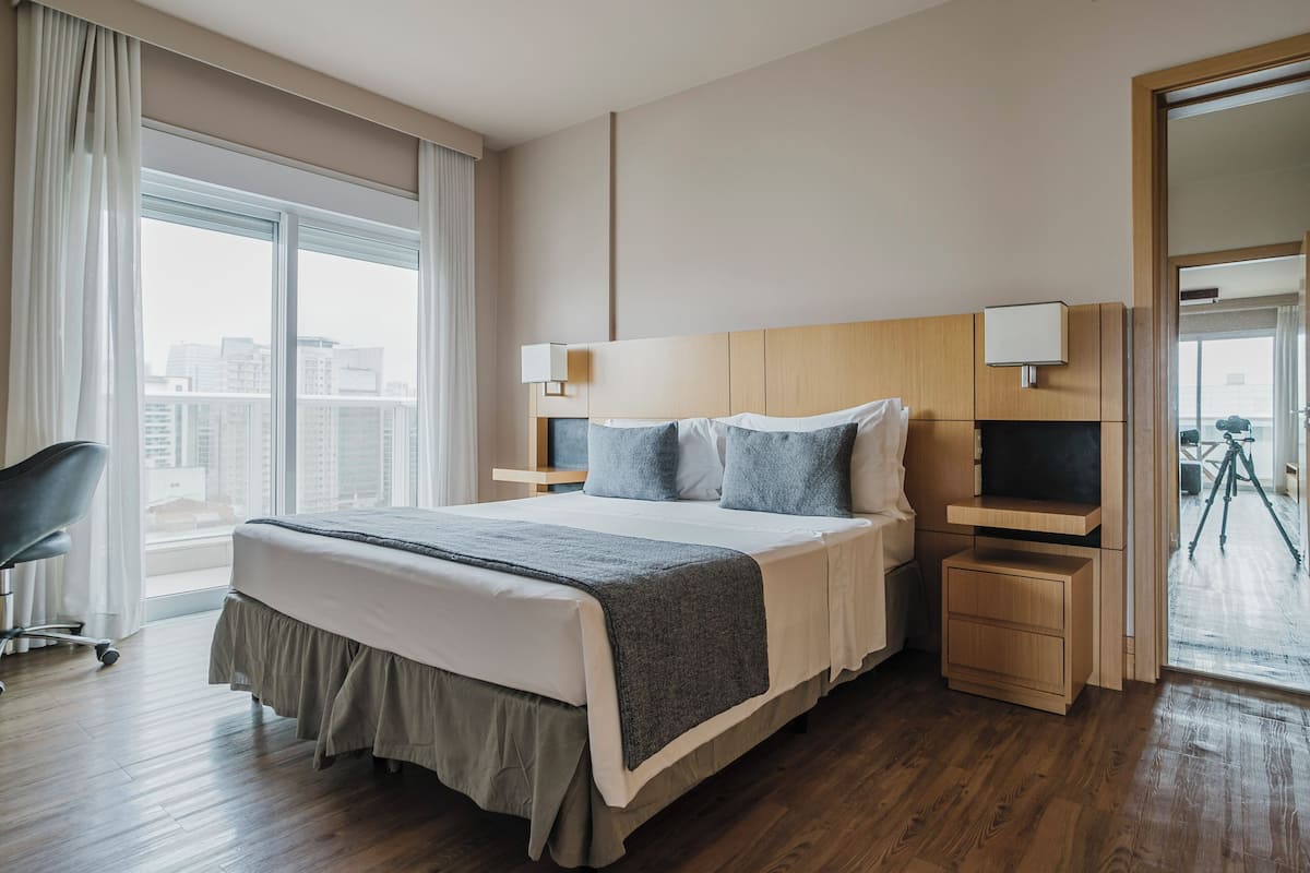 A modern hotel room with a large bed, bedside tables, a desk, and a chair.