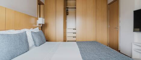 Une chambre d’hôtel avec un lit, une armoire et un téléviseur.