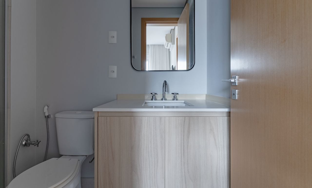 A bathroom with a toilet, sink, and mirror.
