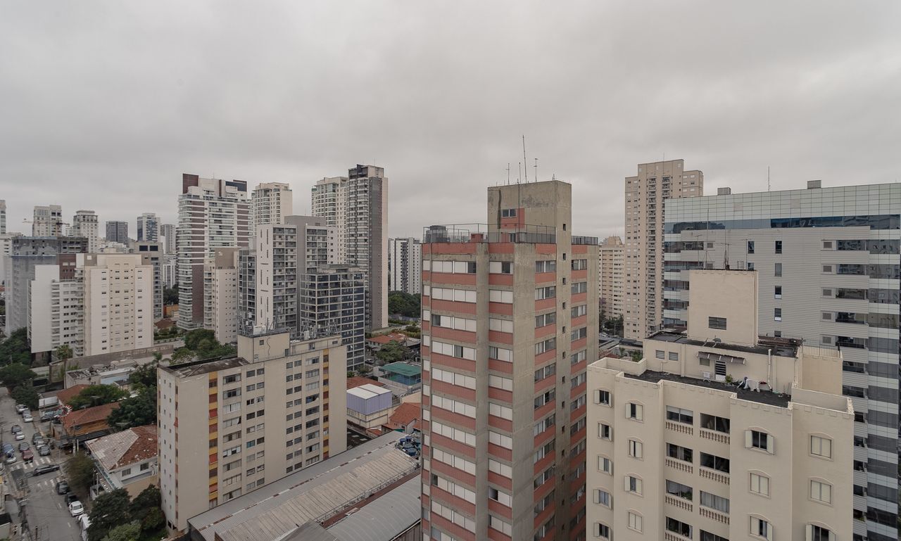 A high-rise urban residential building with multiple floors, balconies, and a dense cityscape in the background.