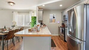 A modern kitchen with a large stainless steel refrigerator, wooden dining table, and chairs. - Private hot tub / Close to town / Cozy and pet friendly (Chelan)