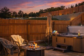 A backyard with a wooden deck, outdoor seating, a hot tub, and a fire pit. - Private hot tub | Walk to downtown Chelan | Cozy and pet friendly (Chelan)