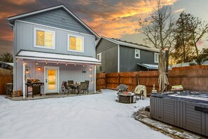 A two-story house with a covered patio, a hot tub, and a barbecue area.