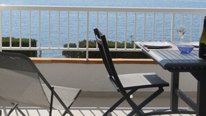 Un balcón con mesa, sillas y vista al mar.