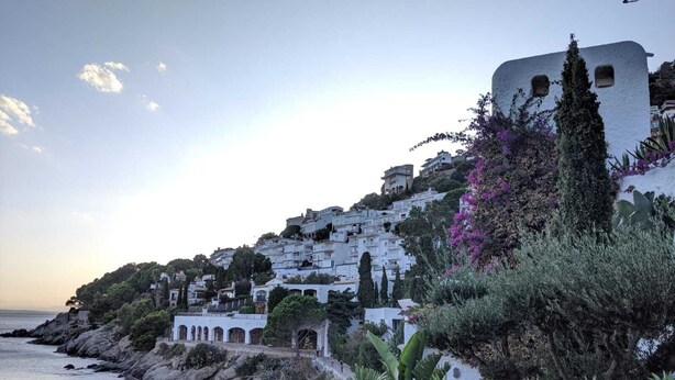 Un pueblo costero con edificios blancos, un litoral rocoso y vistas al mar.