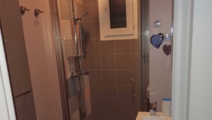 Une petite salle de bain avec une douche à parois de verre, un lavabo blanc et des toilettes.