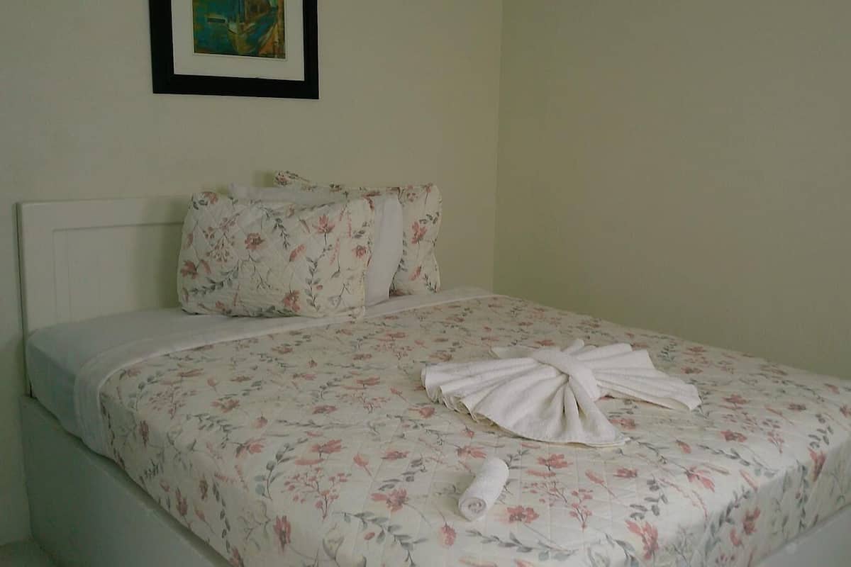 Una cama con ropa de cama floral, cabecera blanca y una toalla sobre la cama.