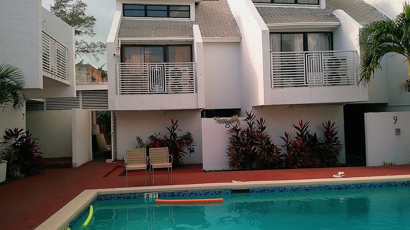 Ein modernes Gebäude mit einem Pool, zwei Balkonen und Sitzgelegenheiten im Freien.