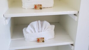 Dos estantes blancos con toallas blancas dobladas y una caja pequeña en cada uno.
